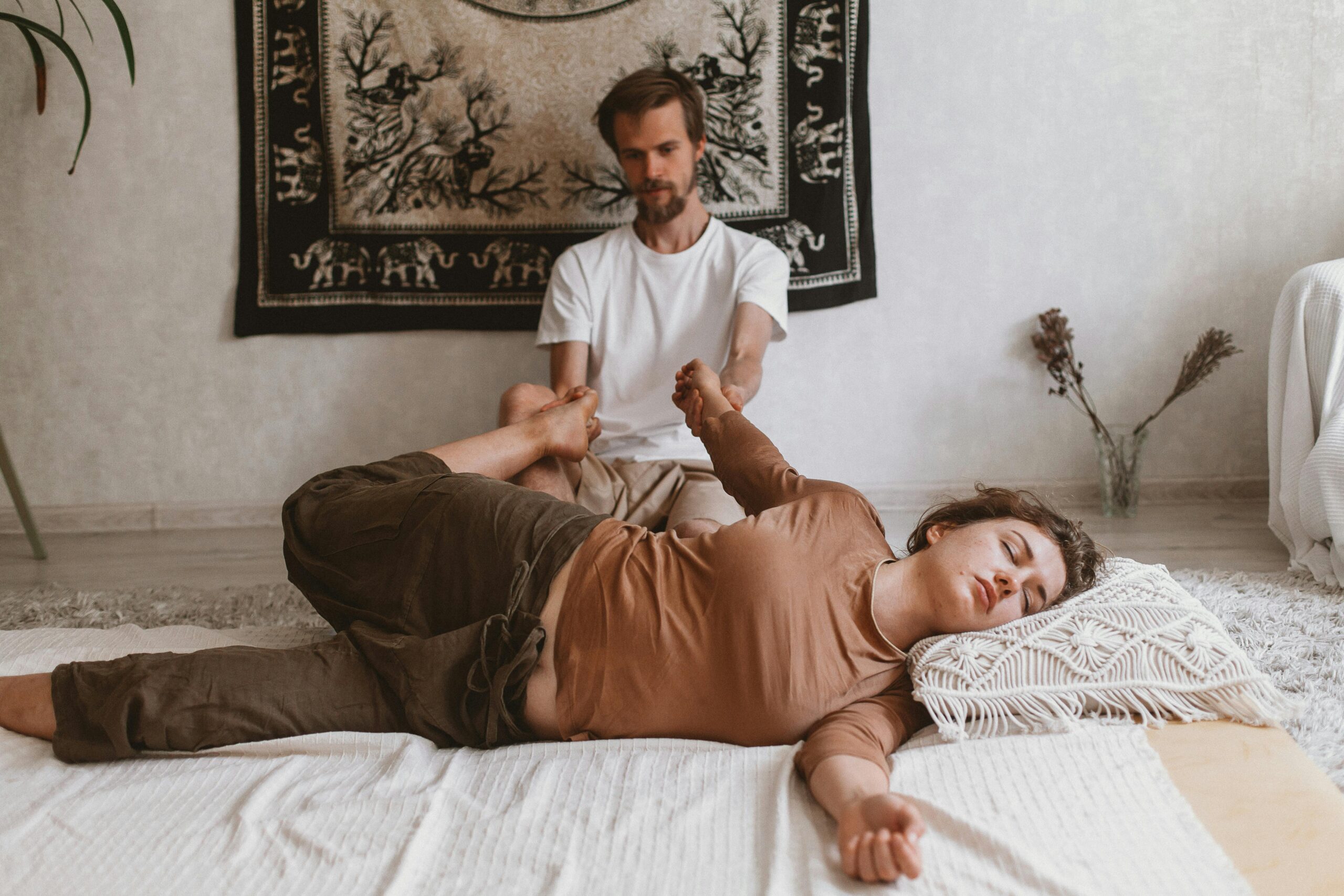 A peaceful Thai massage session with a woman being gently stretched by a therapist in a tranquil setting.