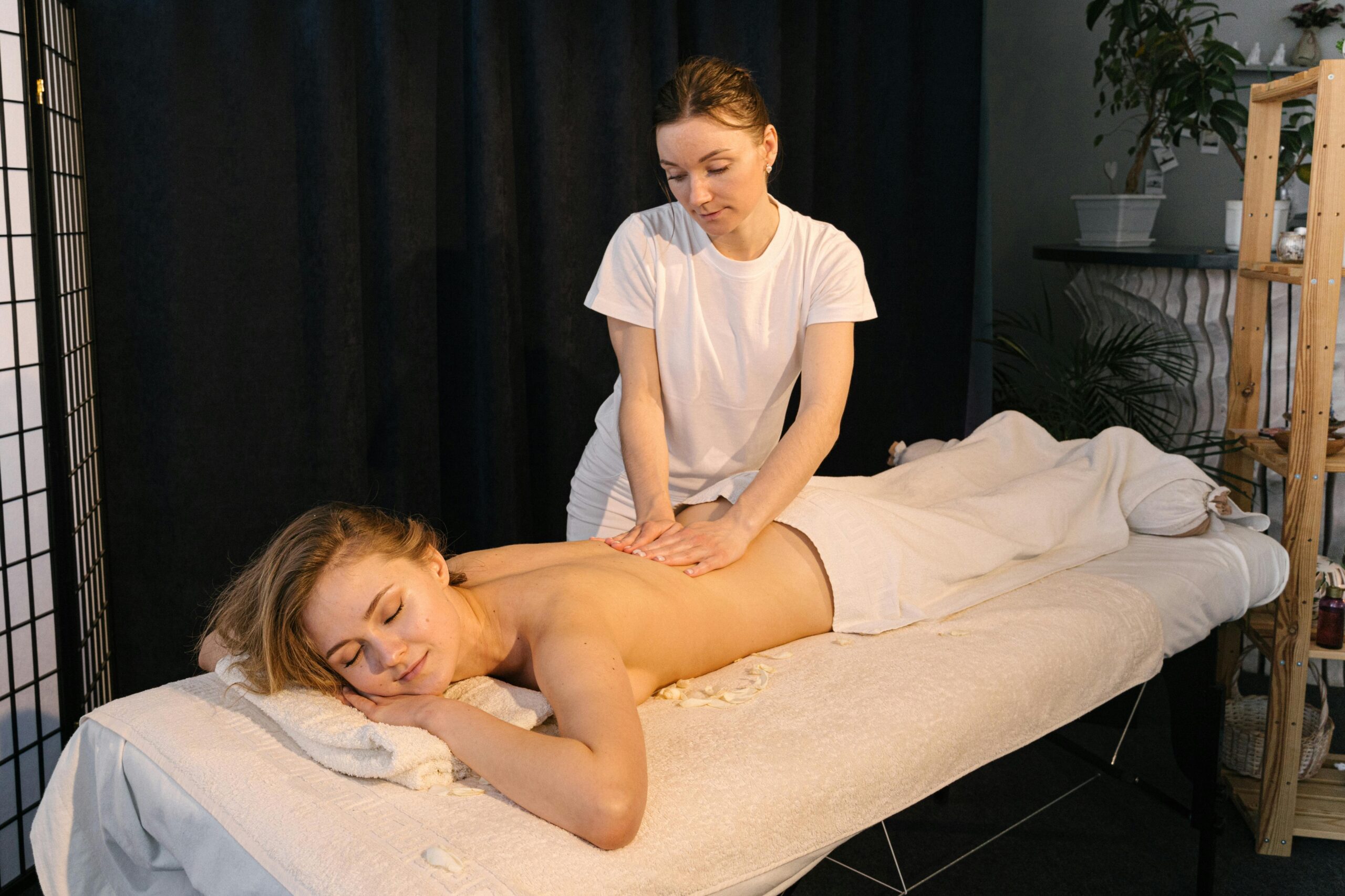 A professional masseuse giving a relaxing back massage in a serene spa setting.